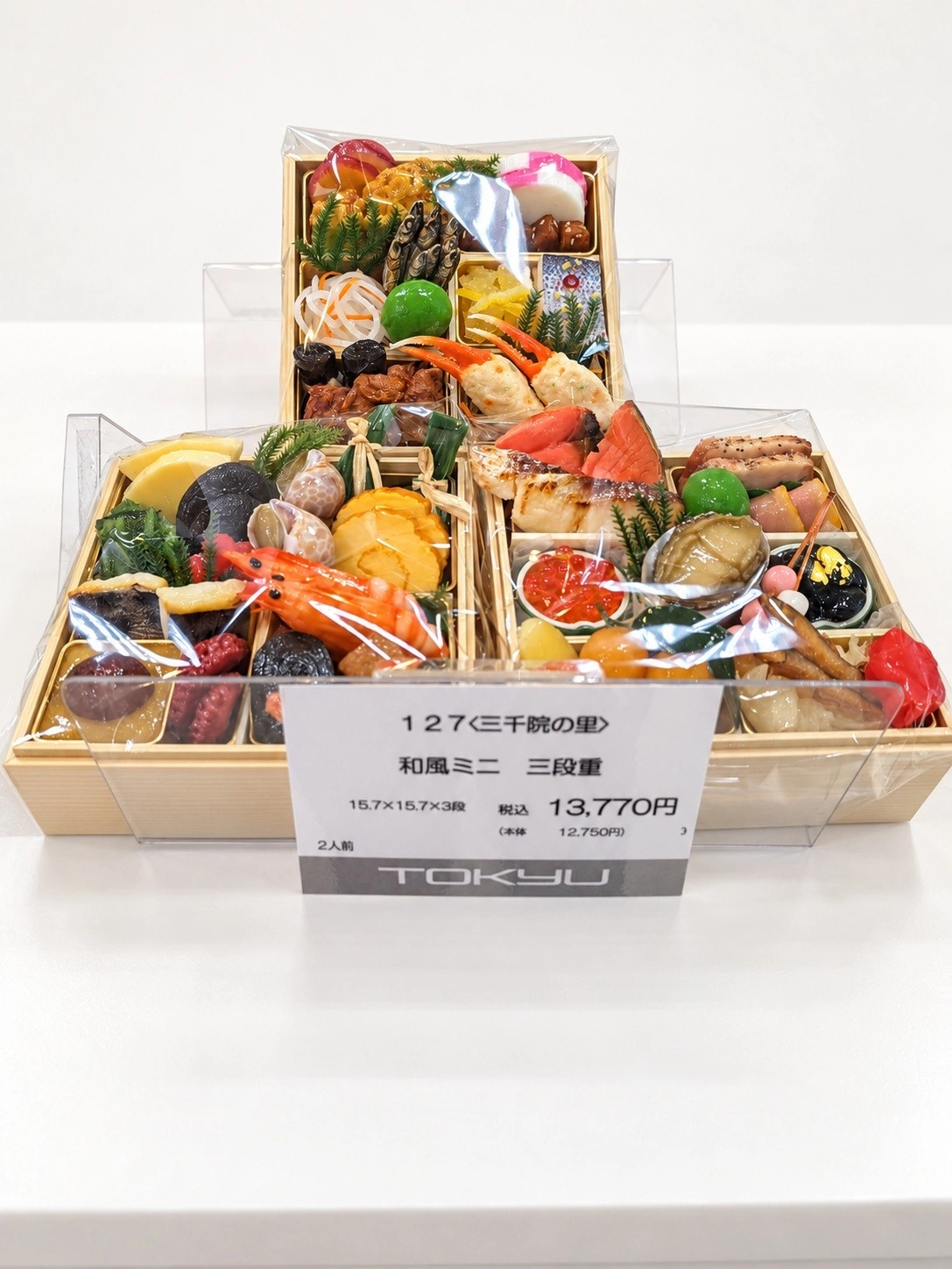 〈三千院の里〉和風ミニ三段重の見本と13,770円の値札（売り場の背景はAIで差し替え）