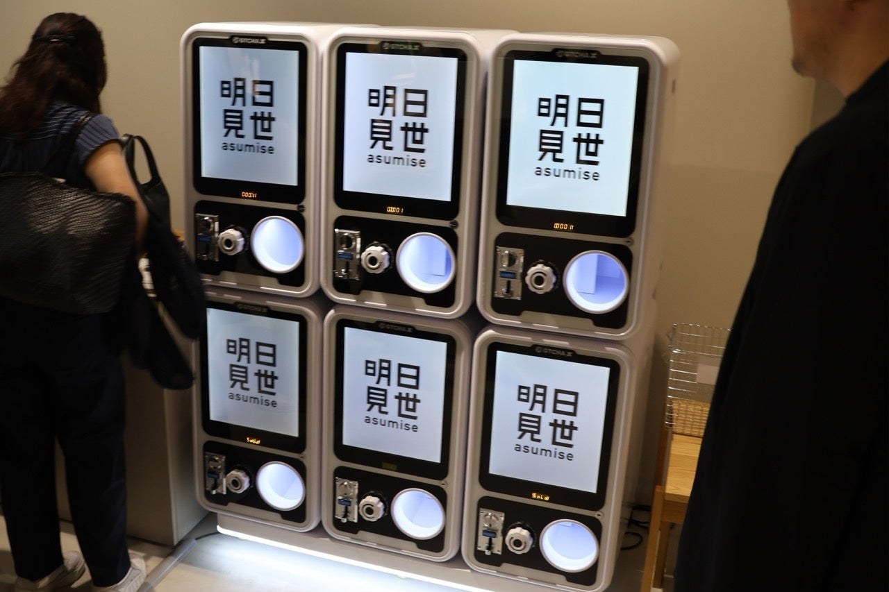大丸東京店9階「明日見世」に並ぶGTCHA X。上下2段で組まれていて、画面には店のロゴが出ている（出典: 株式会社ゼロプレイス）